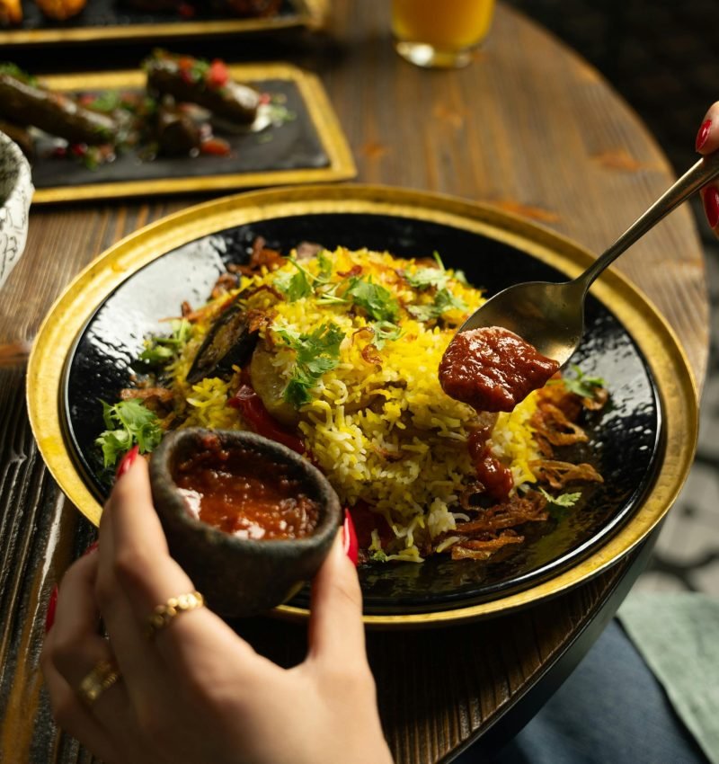 Close-up of traditional Indian rice dish with chutney on a rustic plate.