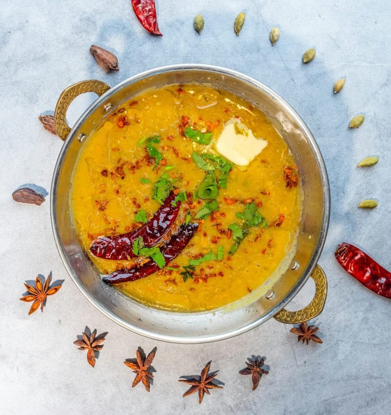 Indian Dal Tadka garnished with spices and herbs, served in a traditional brass bowl. Perfect for authentic cuisine themes.
